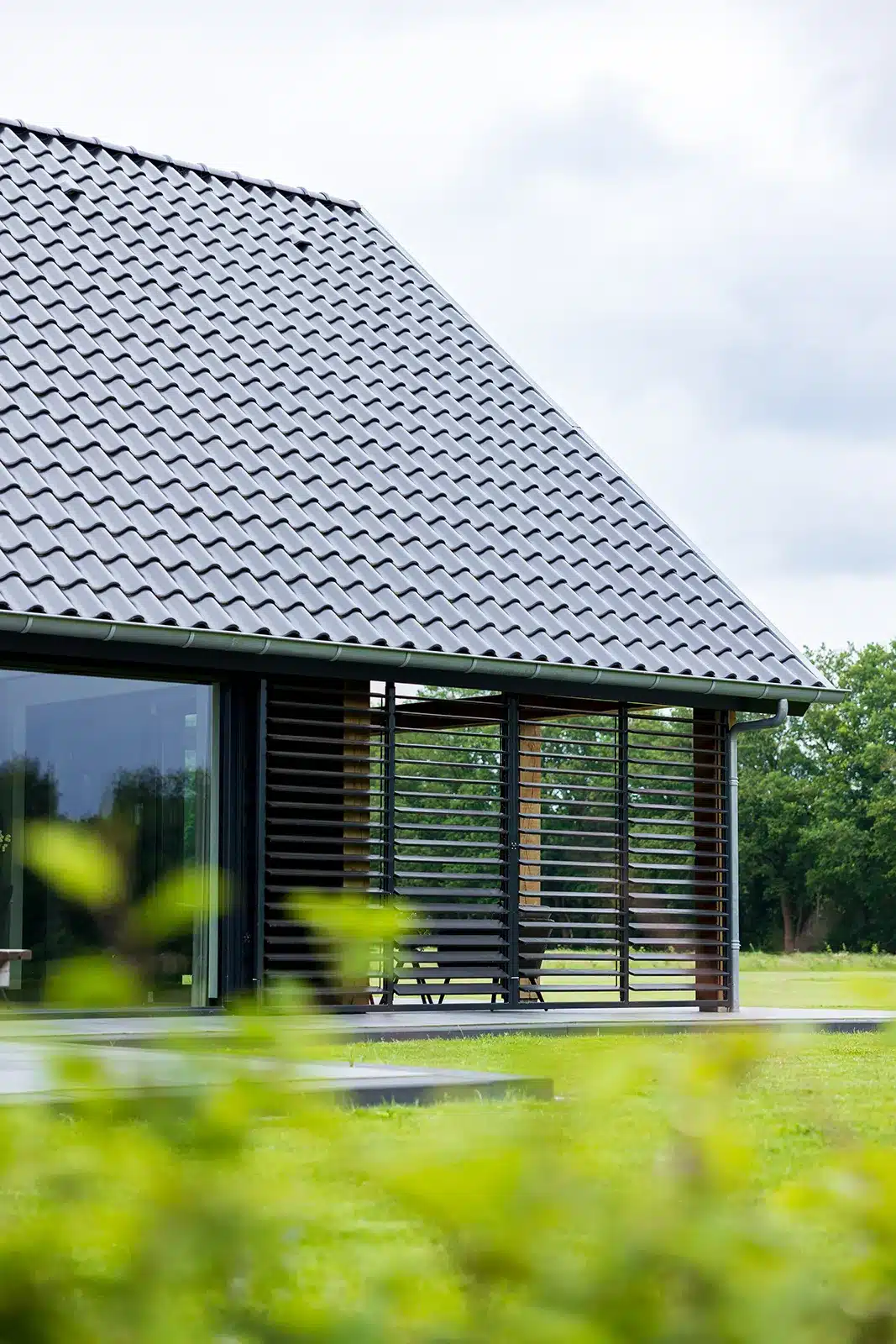 Close-up van de gevel met zwarte houten lamellen en een strak vormgegeven daklijn.