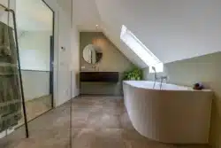 Badkamer met vrijstaand bad, dakraam en natuurlijke tinten.