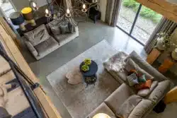 Doorkijk vanuit de vide naar de woonkamer met hoge plafonds en karakteristieke houten balkenconstructie in Okkenbroek.