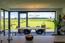 Eetkamer met grote glaspartijen en uitzicht op het weidse landschap in Olst.