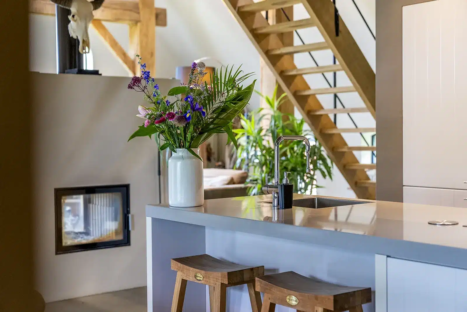 Keuken met houten trap, lichte inrichting en natuurlijke materialen, onderdeel van de verbouwde boerderijwoning in Okkenbroek.