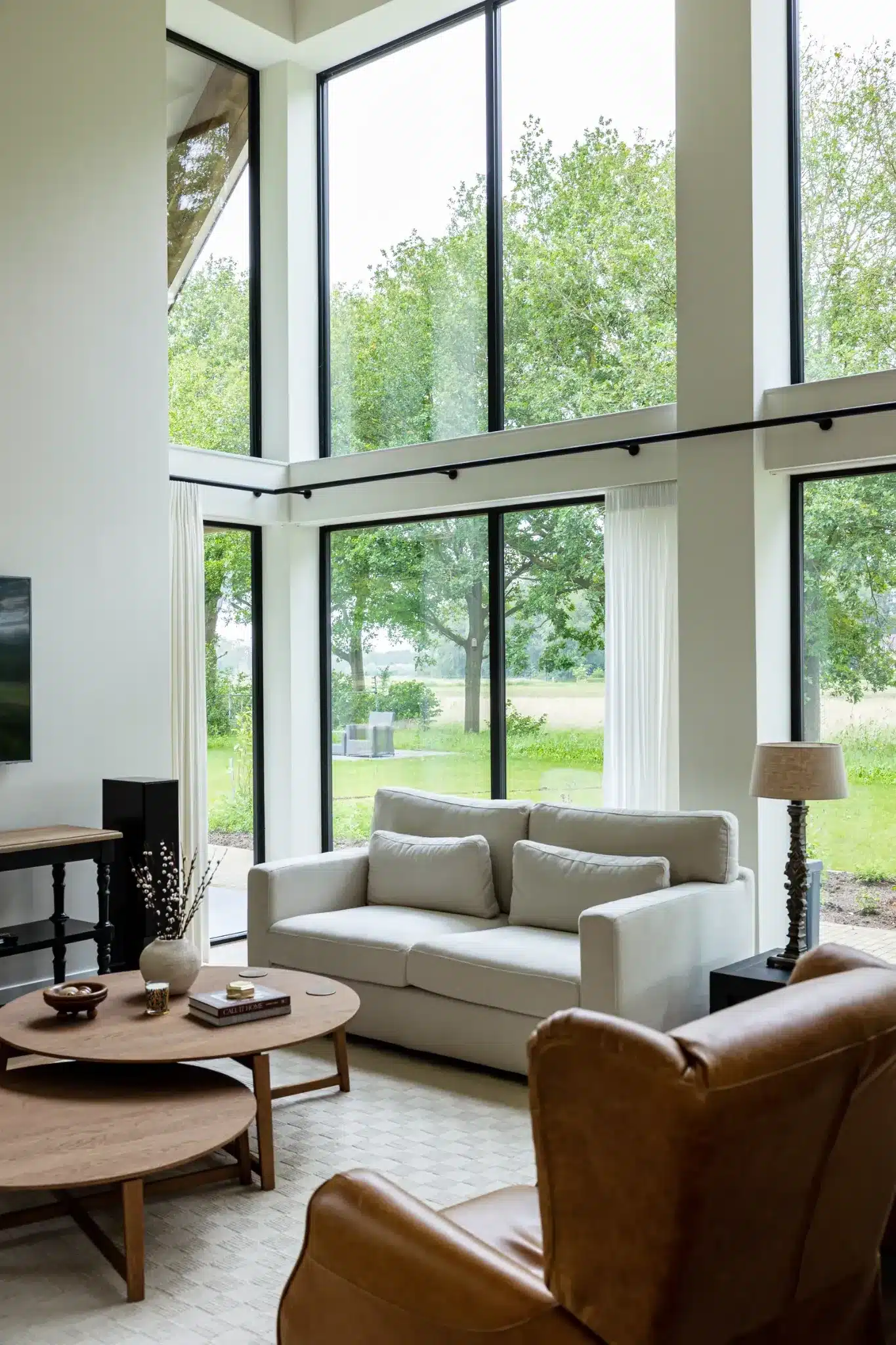 Zithoek in de woonkamer met grote ramen tot aan de vloer en uitzicht op het landschap in Wesepe.