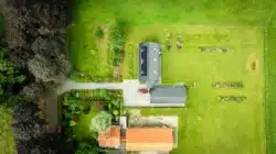 Luchtfoto van de rood voor rood schuurwoning in Olst met zonnepanelen en ruime groene tuin.