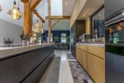 Moderne keuken in Okkenbroek met robuuste houten balken, donkere accenten en stijlvolle verlichting.