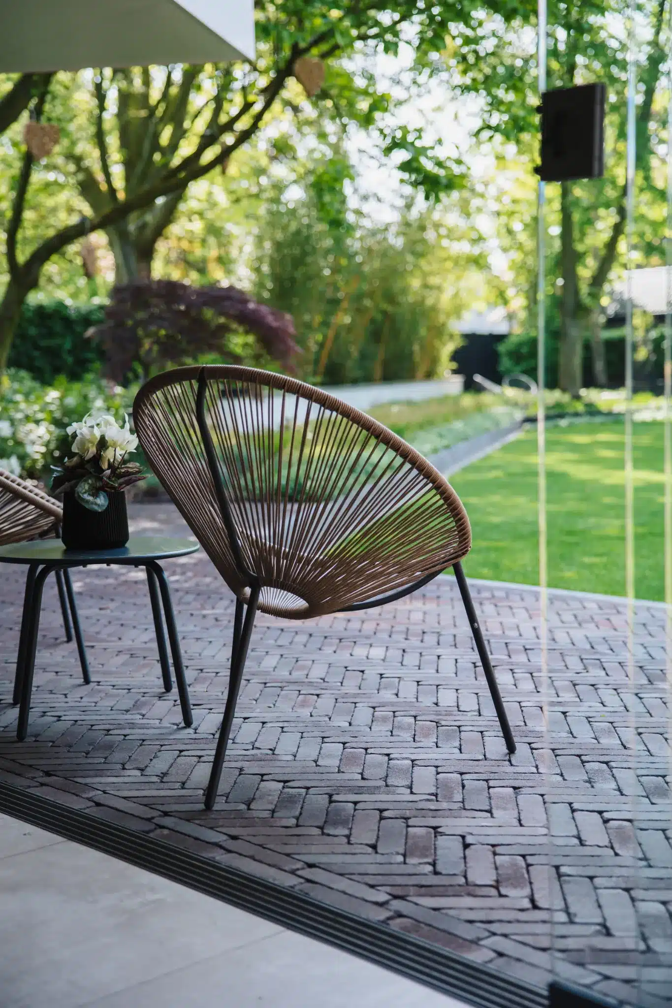 Zitplek bij de woning in Raalte met tuinstoel op een bakstenen terras en uitzicht op de groene tuin.