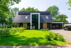 Voorgevel van de moderne nieuwbouwwoning aan de Hiethaarshoek in Wesepe met zonnepanelen en veel glas.