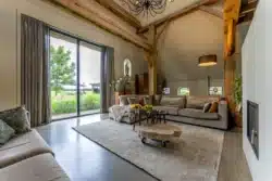 Woonkamer met zichtbare houten balken, warme inrichting en uitzicht op het Sallandse landschap in Okkenbroek.