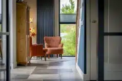 Zithoek met rode stoelen, houten kast en veel daglicht; sfeervolle ruimte in de nieuwbouwwoning in Deventer.