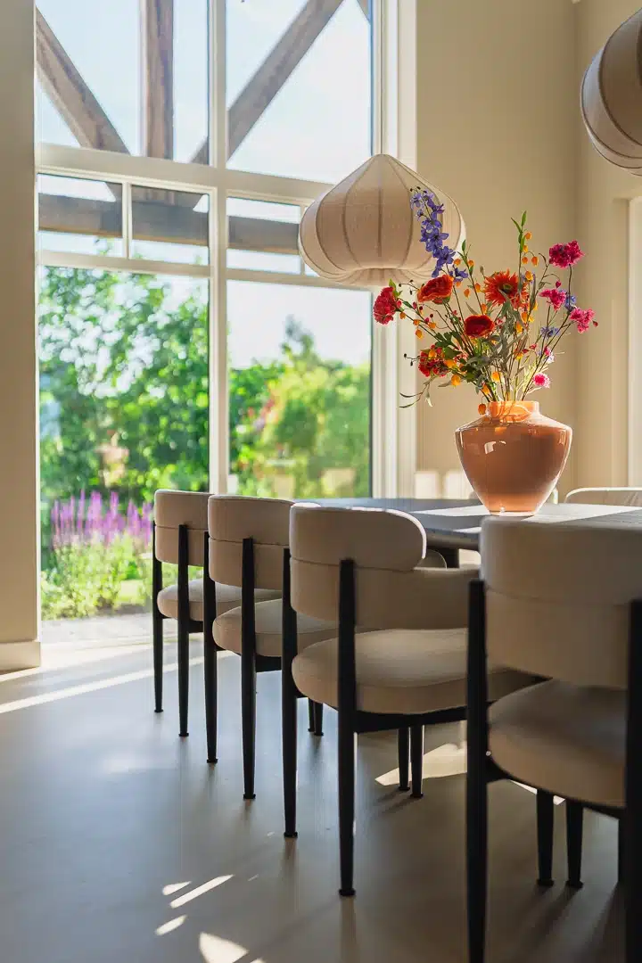 Moderne eethoek in een nieuwbouwwoning in Mariënheem met hoge glaspartij, design hanglampen, een donkere eettafel en uitzicht op de groene tuin.